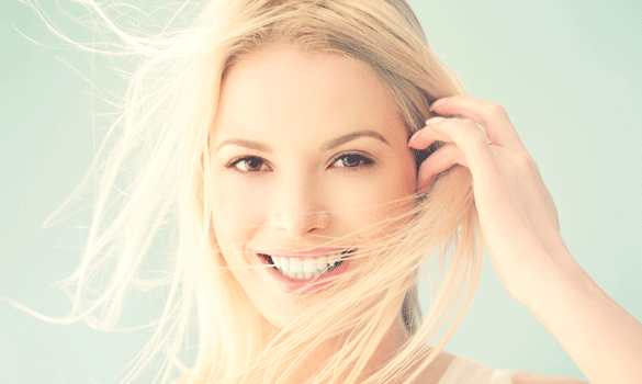 Smiling woman pulling her blonde hair out of her face