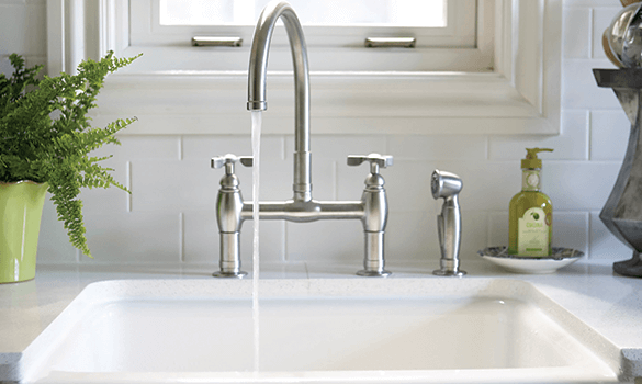 A water faucet pouring water into a white sink