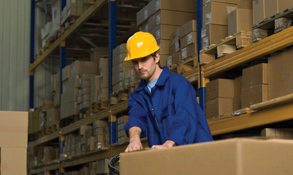 Man in a blue shirt and yellow hard hat pulling a package at a distribution center