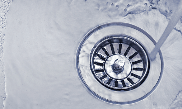 Water pouring down the drain of a stainless steel sink