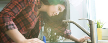 Woman looking at her water faucet in the kitchen