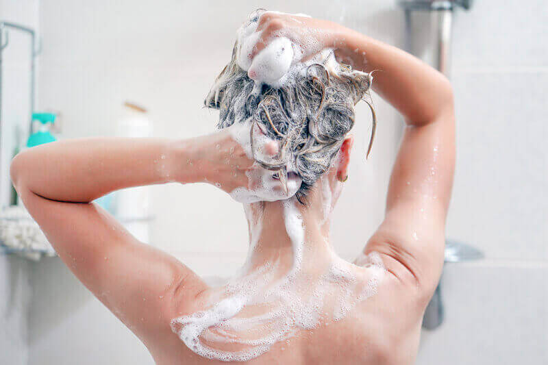 A woman washing her hair in the shower.