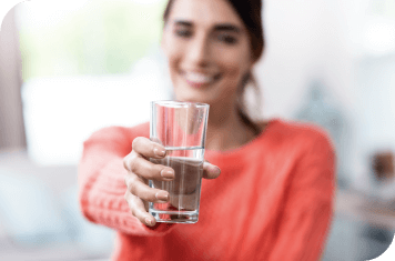 faded woman in orange shirt holding out a glass of water