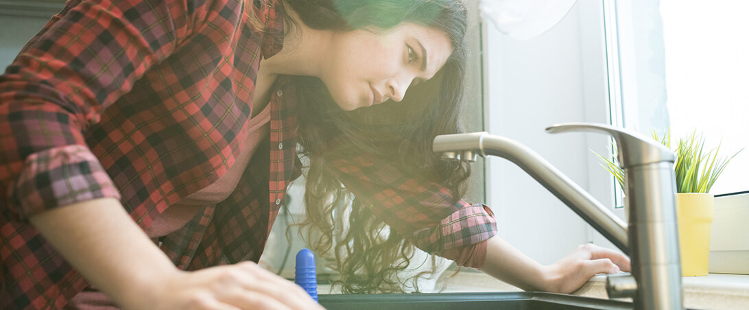 A woman staring at a kitchen sink.