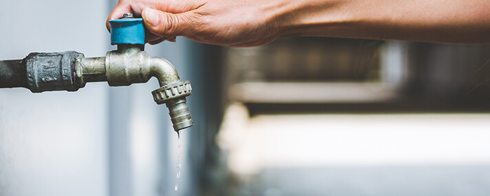 A hand on a water faucet