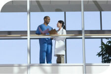 Two healthcare professionals talking in a hallway.