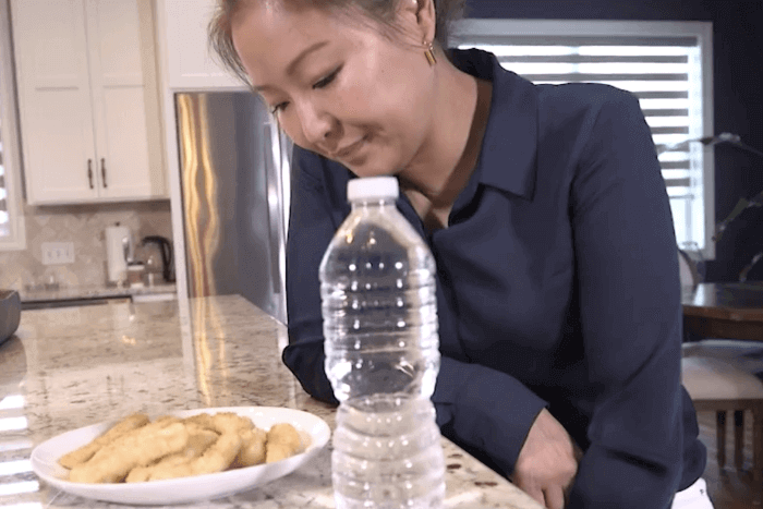 A woman smiling down at a plate of wood with a water bottle.